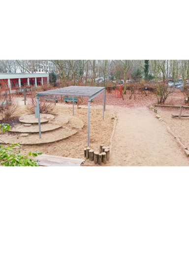 Spielplatz mit Sandfläche, Holzstämmen und Klettergerüst in einer grünen Umgebung.
